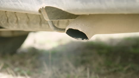 dirty tailpipe coughs exhaust as vehicle starts, close-up