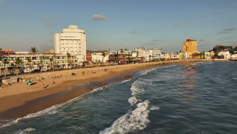 Luftbild-Kamerafahrt-Vor-Menschen-An-Einem-Strand,-Goldene-Stunde-In-Mazatlan,-Mexiko