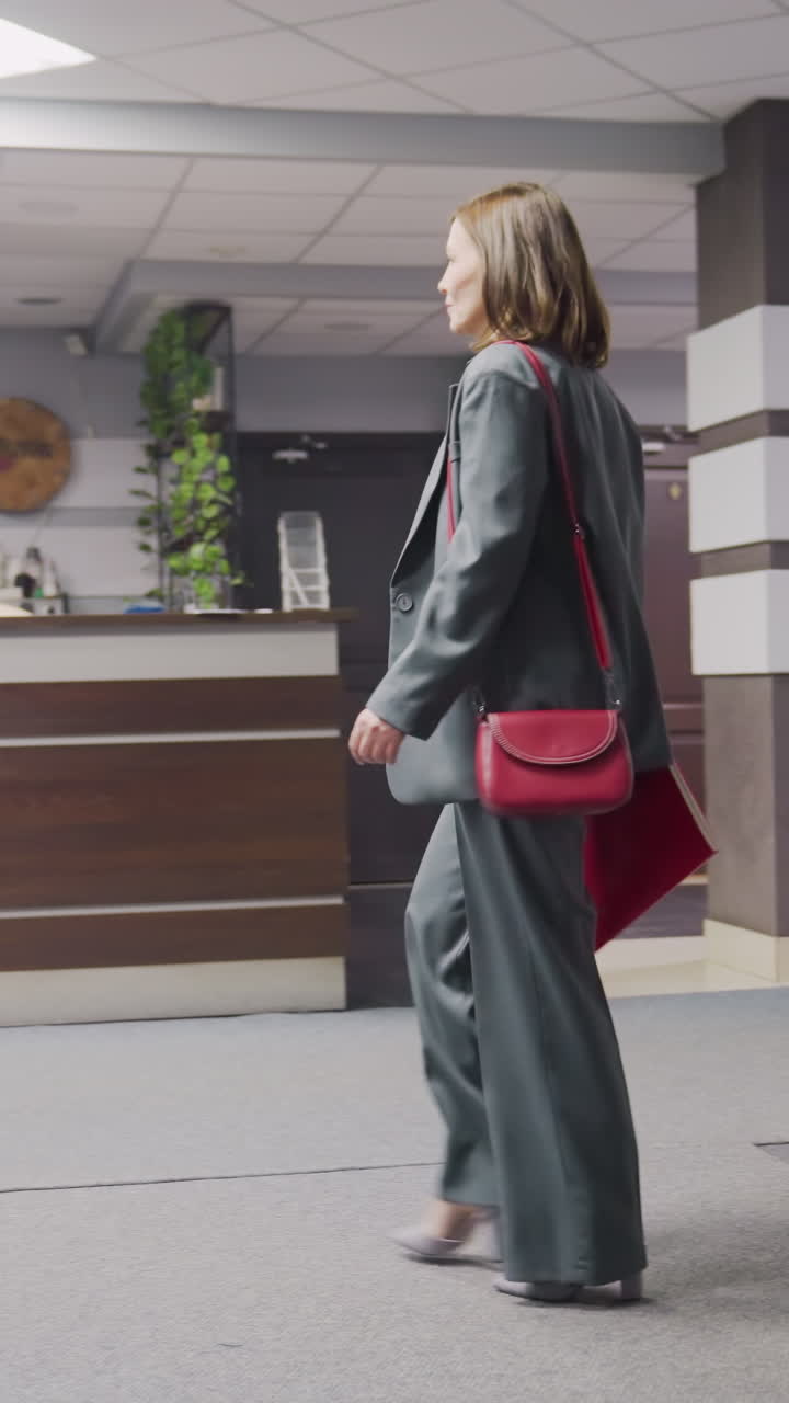 Businesswoman in formal attire walking down office stairwell carrying folder, professional office interior, modern workplace, confident woman in business setting