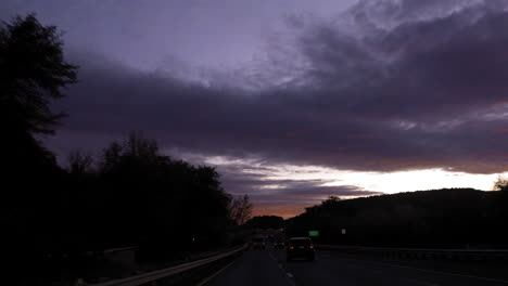 conduciendo a lo largo de una carretera oscura al atardecer con hermosas nubes azules púrpuras - fpv
