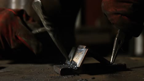 manos de un soldador trabajando en una pieza de metal