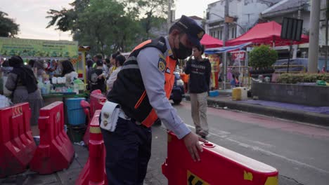 security guard arranges traffic barriers at a bustling street market