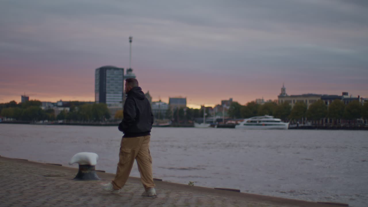 A Greek European male man guy model walks on the streets of Rotterdam with city town evening sunset view