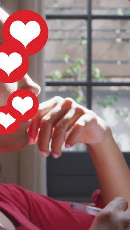 animación de iconos de corazones digitales sobre una mujer escuchando música con auriculares escribiendo en casa