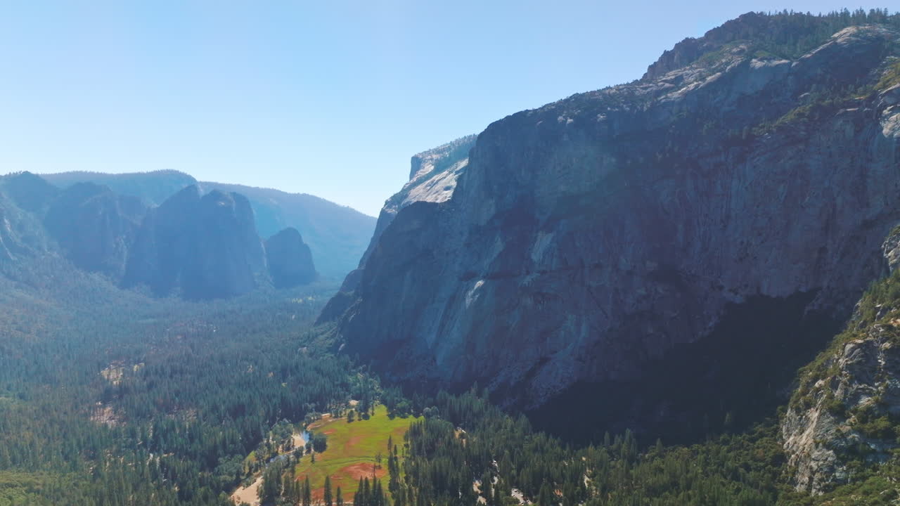 Sunlit pine tree forest surrounded by powerful rocks. National Park of Yosemite, California, USA from aerial view.