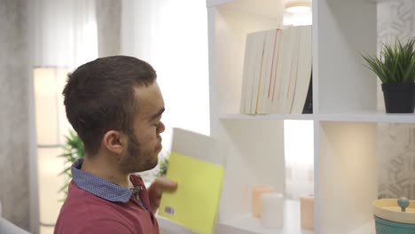 un joven enano discapacitado toma libros de la estantería de su casa y comienza a leer.