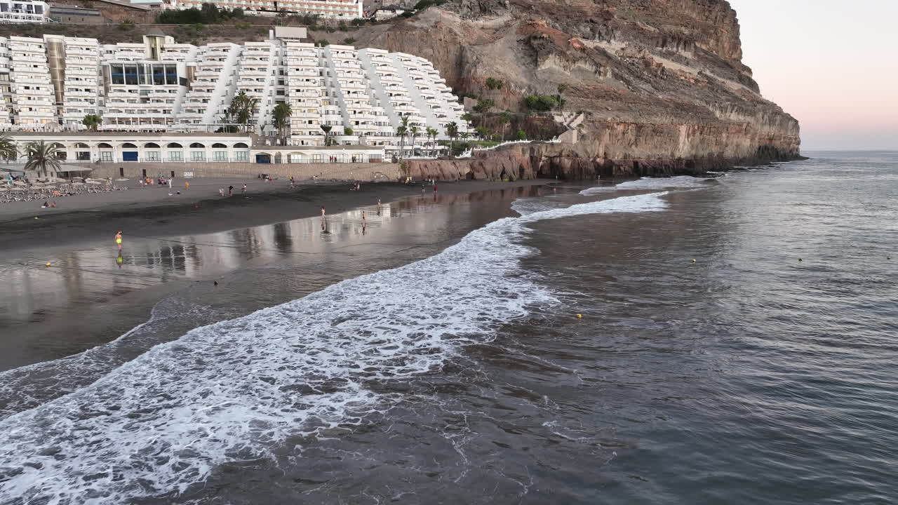 toma aerea en la orilla de la playa taurito en mogan y donde se puede ver gente bañándose