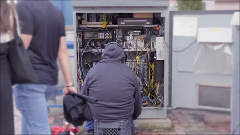reparador sentado frente a una caja de panel eléctrico abierta en la acera en boston, massachusetts, ee.uu.