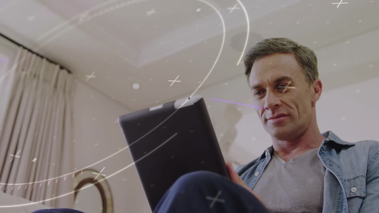 Man on couch lifting tablet entering frame, tilting while reviewing content, tech overlay sweeping