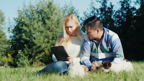 Couple-With-Puppies-and-Tablet-in-Backyard