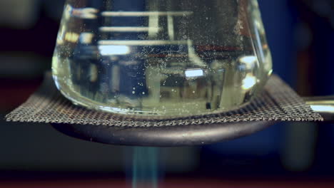 close up of erlenmyer flask that is being heated by a bunsen burner less condensation on top, heat waves visible in flask, bubbles beginning to form