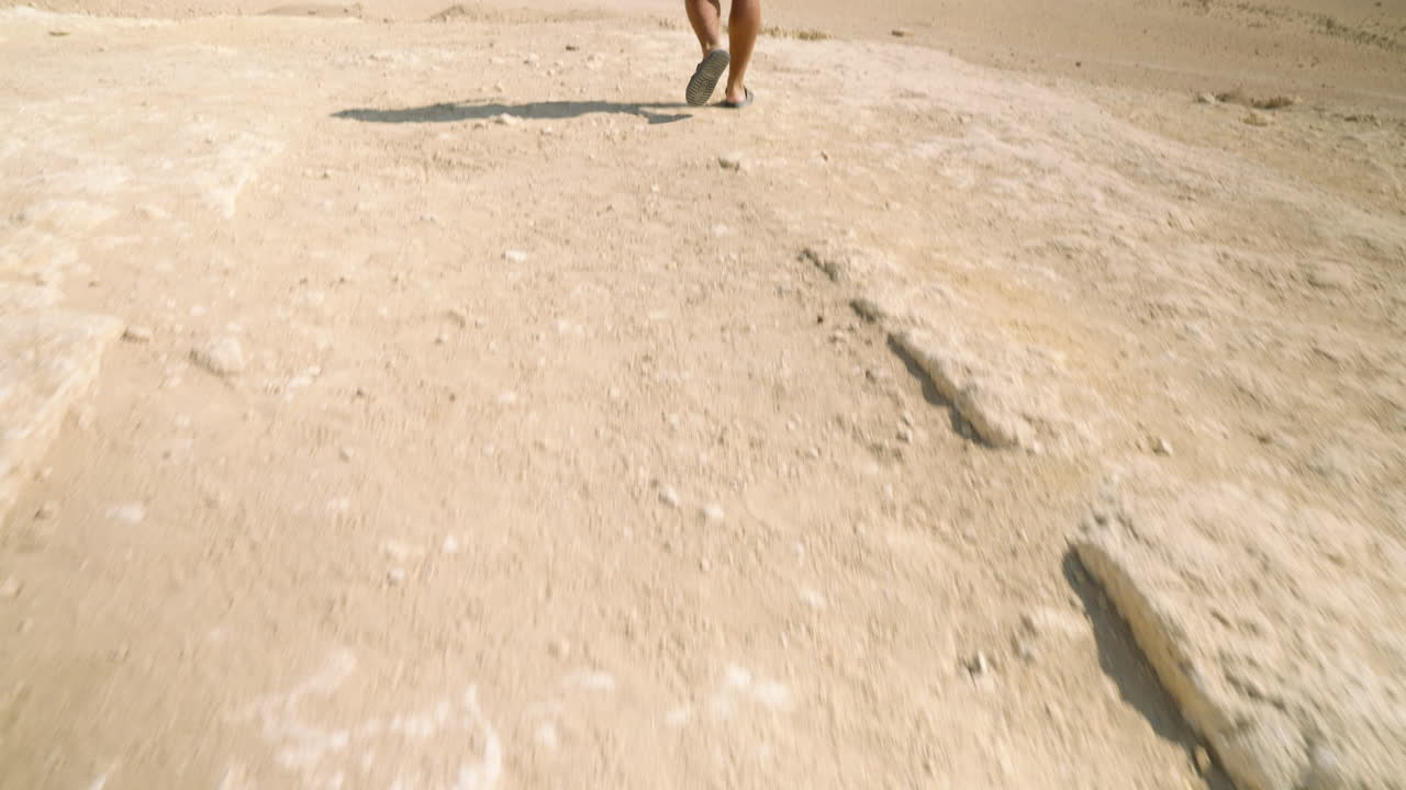 Reveal A Man Walking Over Dried Foreground Near Giza Necropolis Near Cairo, Egypt. Tilt-up Shot