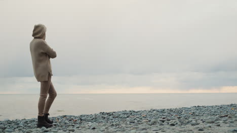 a woman in a warm knitted sweater looks at the sea where the storm begins