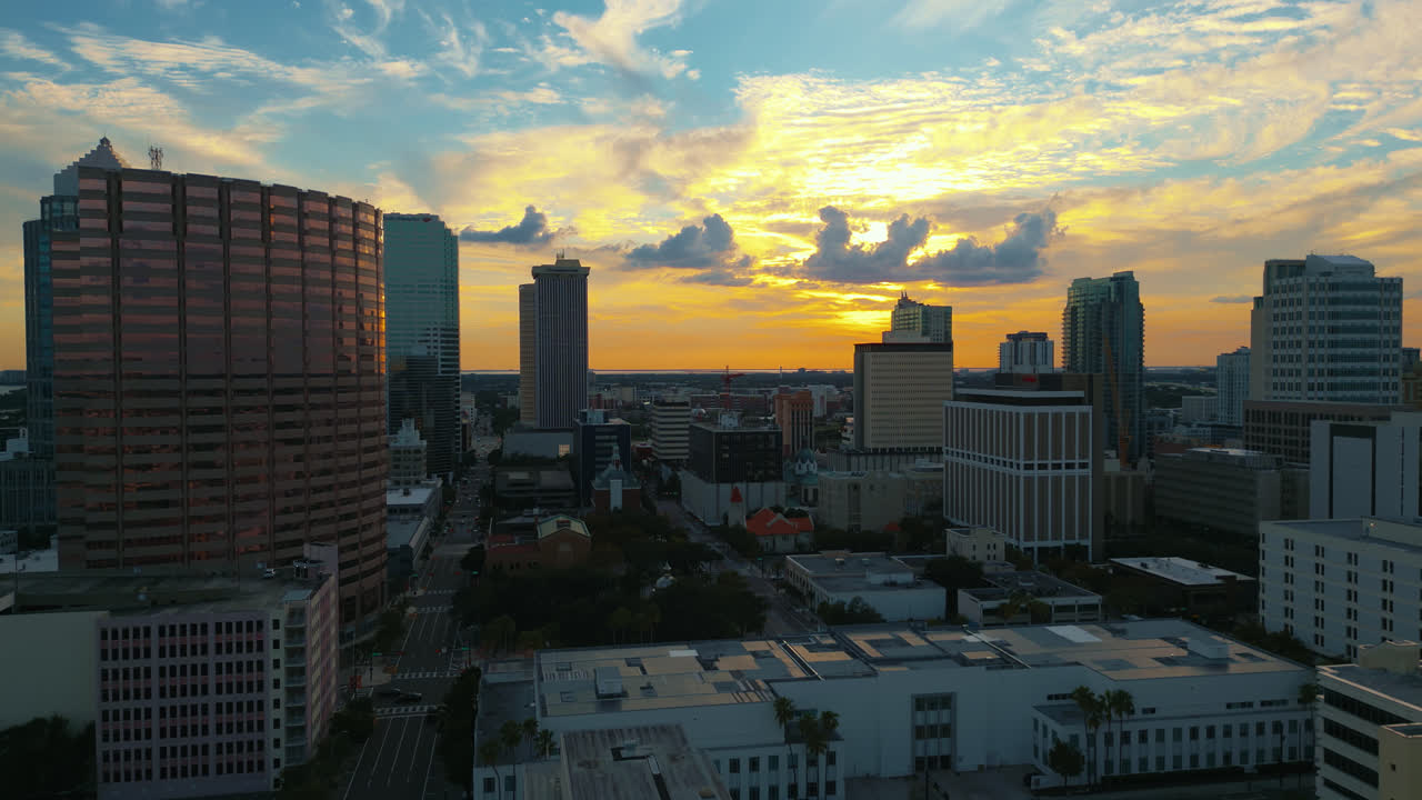 Tampa skyline as the day ends and sunset begins with golden light reflecting off of buildings, aerial flying forward