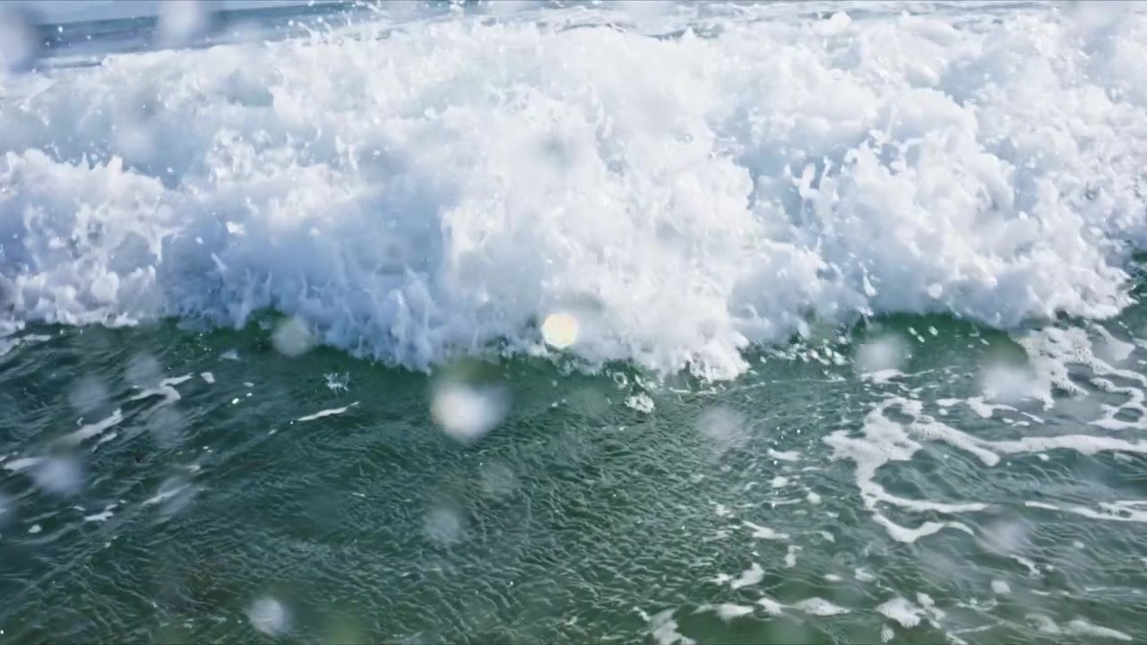 Dynamic water level shot in Tarifa, Spain capturing breaking waves, rolling barrels, white water and crystal clear turquoise Atlantic water with immersive ocean perspective.
