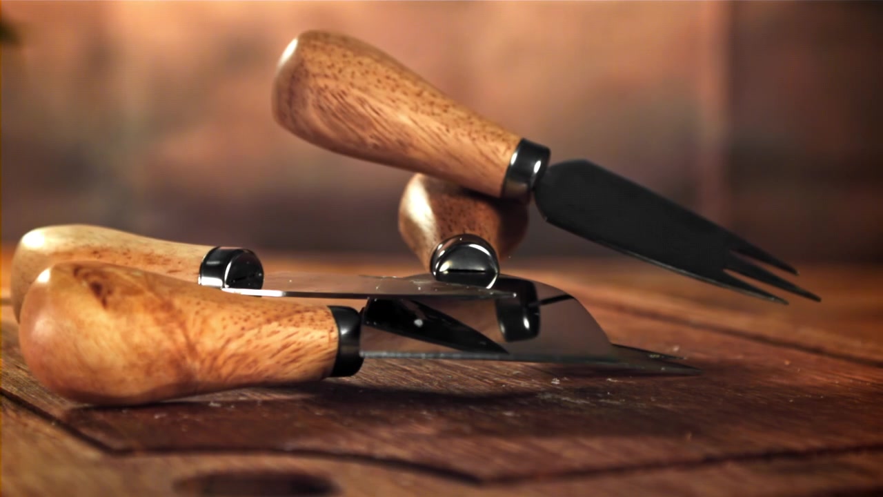 Ralenti de couteaux à fromage tombant sur une planche en bois rustique.