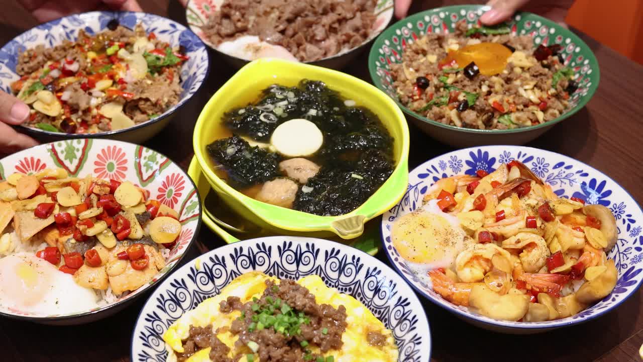 A variety of colorful Thai rice dishes are gradually cleared, leaving a single bowl with seaweed and egg on a wooden table under warm lighting