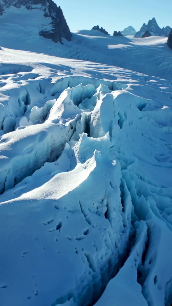 Video verticale: Drone che scende verso un crepaccio glaciale, mostrando ghiaccio blu e seracchi per un rilievo.