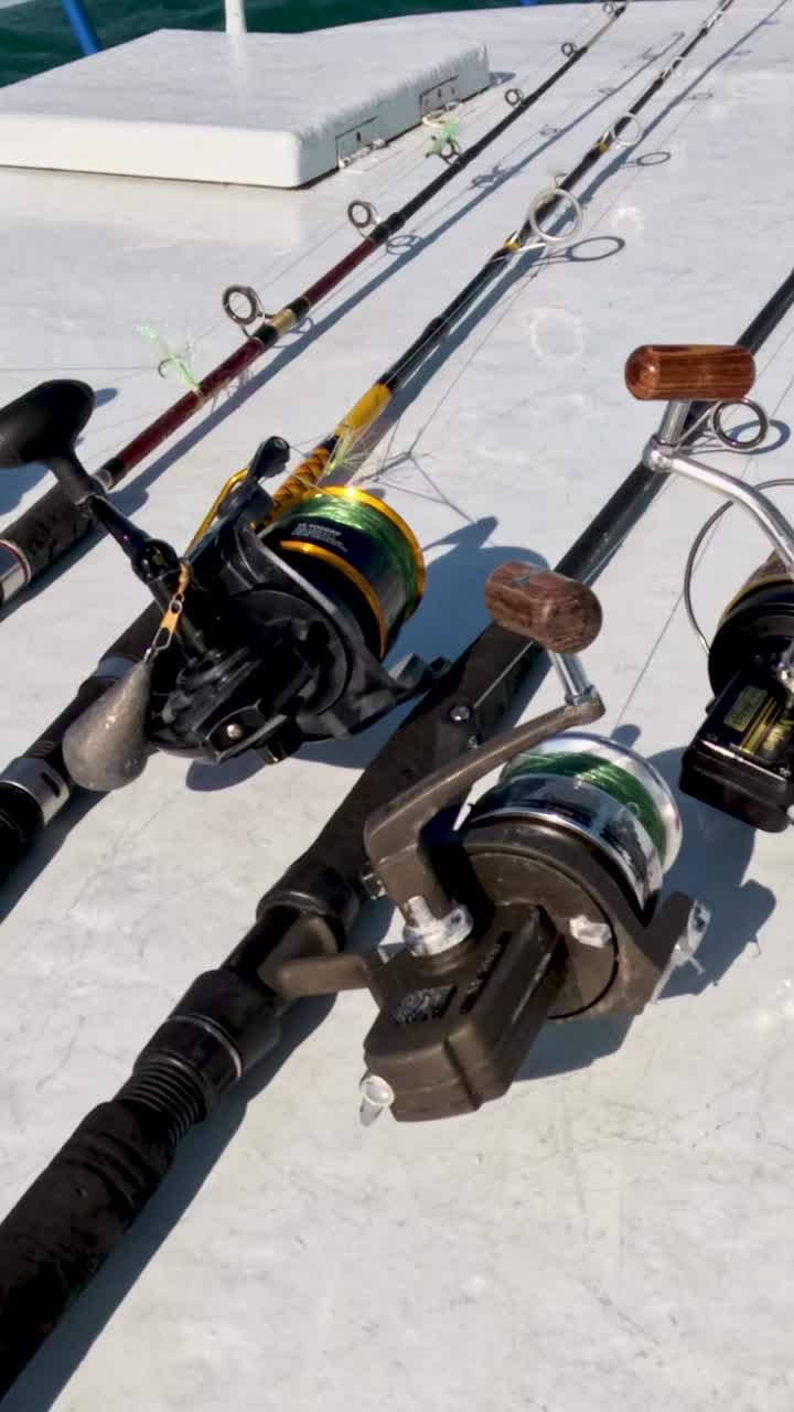 las varas de pesca bien dispuestas en una cubierta de barco bajo la brillante luz del sol, con el telón de fondo de las aguas azules claras de phuket