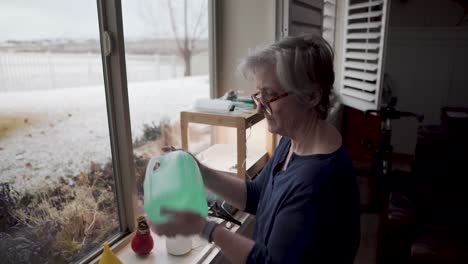 Mujer-Madura-Mezcla-El-Agua-Fertilizada-Y-Balanceada-Para-Su-Jardín-Interior-Hidropónico-Con-Nieve-Afuera