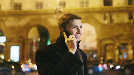 Young-man-talking-on-the-phone-against-the-backdrop-of-a-night-city