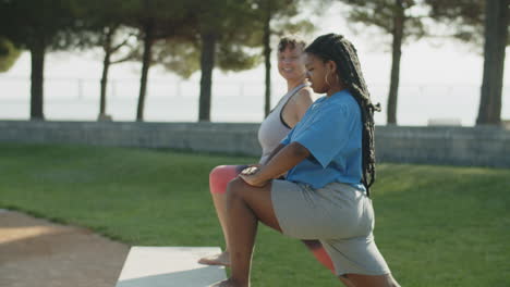 mujeres positivas de cuerpo diverso estirando las piernas en el parque público
