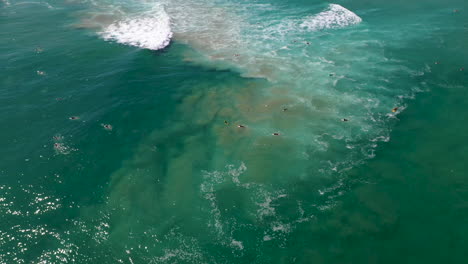 Rotierende-Drohnenaufnahme-Von-Surfern-Im-Ozean,-Die-Am-Strand-Von-Wategos-In-Australien-Auf-Eine-Welle-Warten