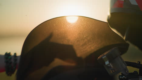 a close-up of a person s hand, adorned with a green bracelet, cleaning the windshield of a motorcycle