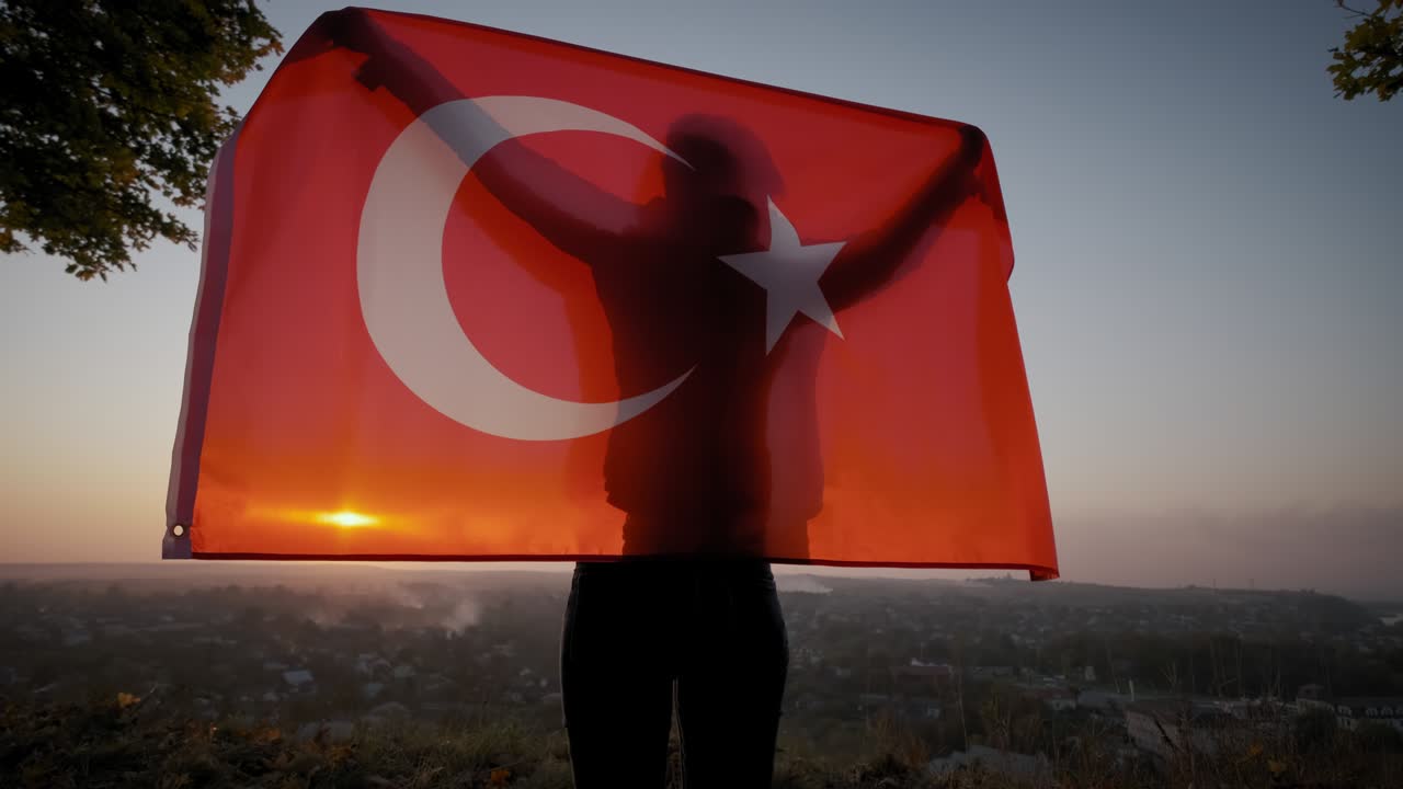 Gün batımında dışarıda duran, Türk ulusal bayraklı mutlu bir kadının arkadan görünüşü.