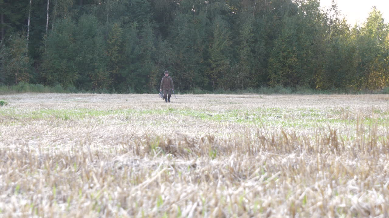 먹이와 무기를 들고 시골 들판을 걷는 성공적인 선임 사냥꾼, 10비트 평면 색상 프로파일