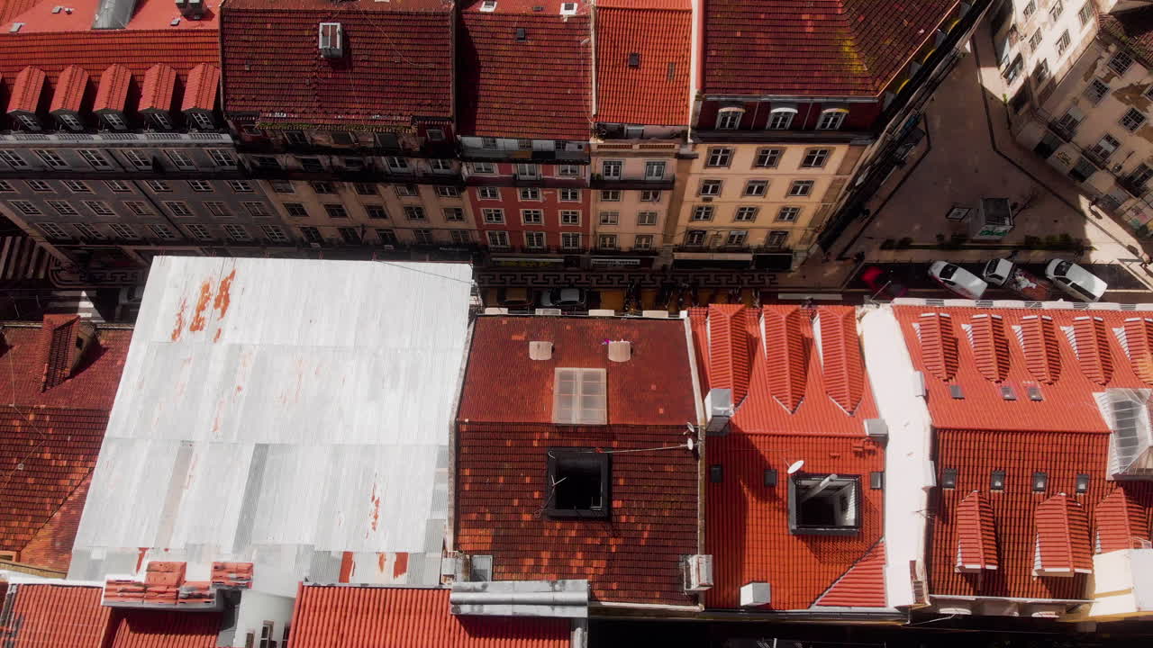 Drone tilting down to top view over Lisbon rooftops and street