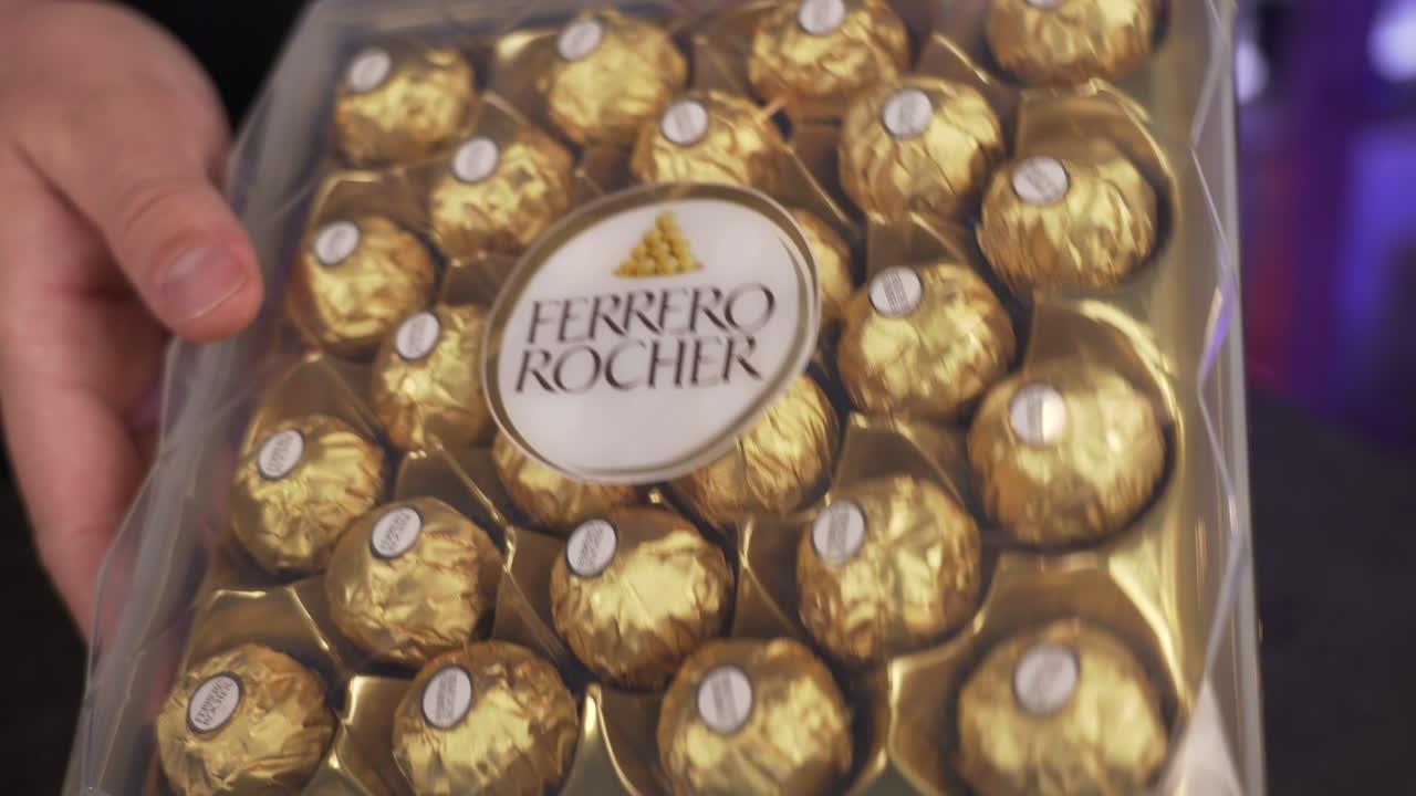 Showing a beautiful Ferrero Rocher box with chocolate candy balls, fancy golden packaging, famous popular sweet dessert treat, the perfect holiday gift, 4K shot