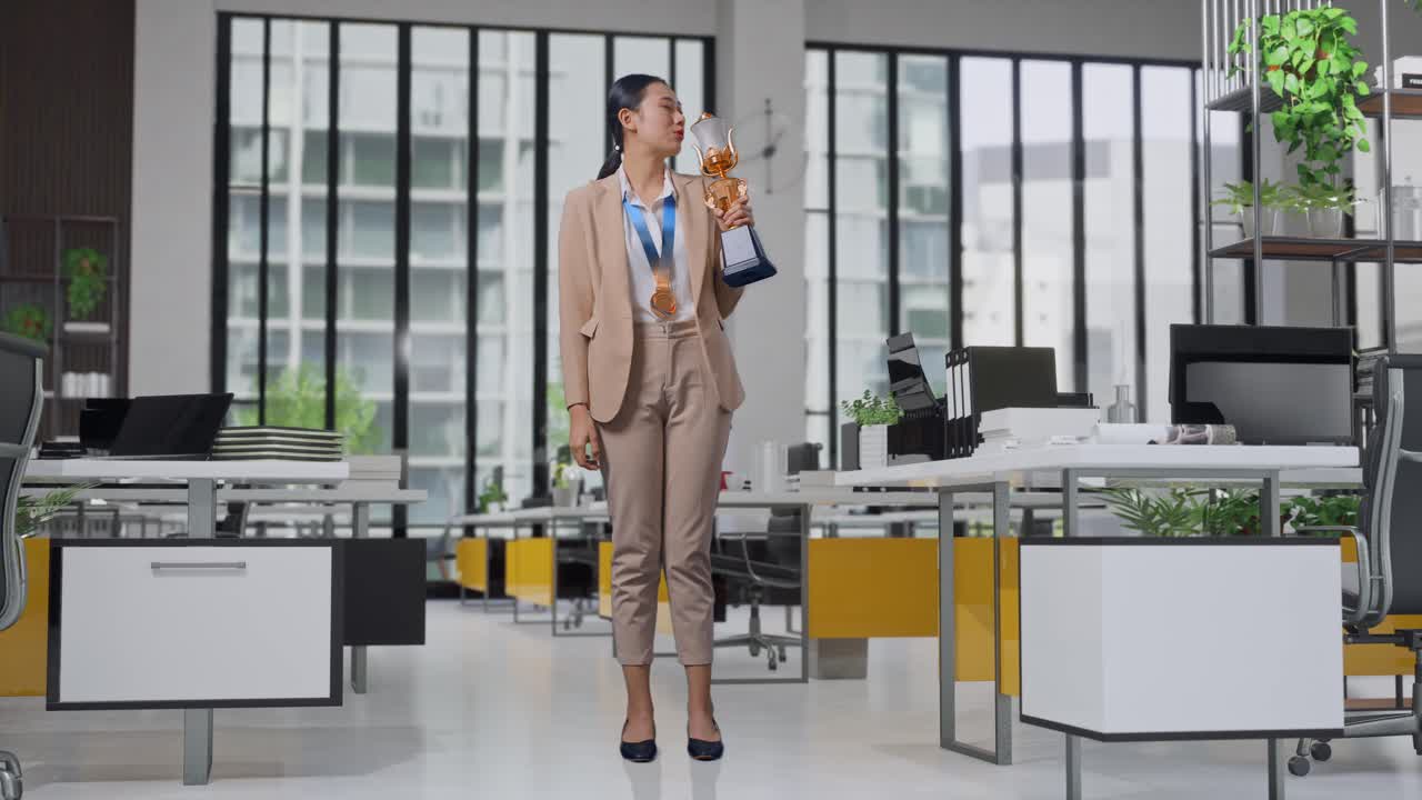 Full Body Of Asian Business Woman In A Suit With A Gold Medal Kissing A Gold Trophy Being Proud Winning As The First Winner In The Office