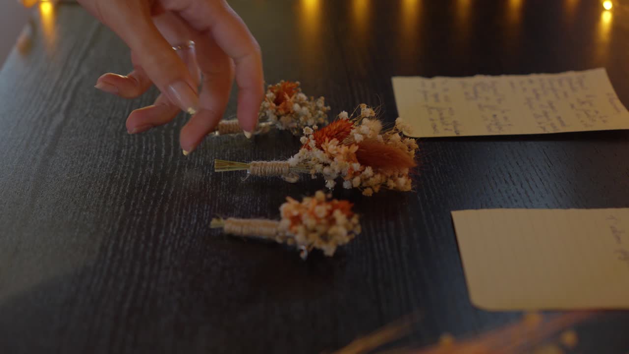 slow revealing shot of multiple boutonnieres sitting on a table beside notes