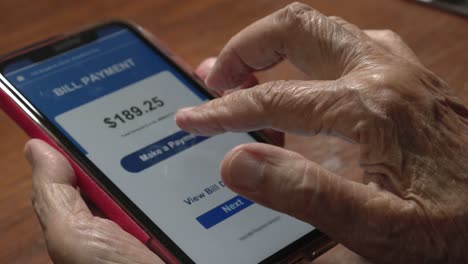 elderly woman confused and  trying to pay bill on cellphone