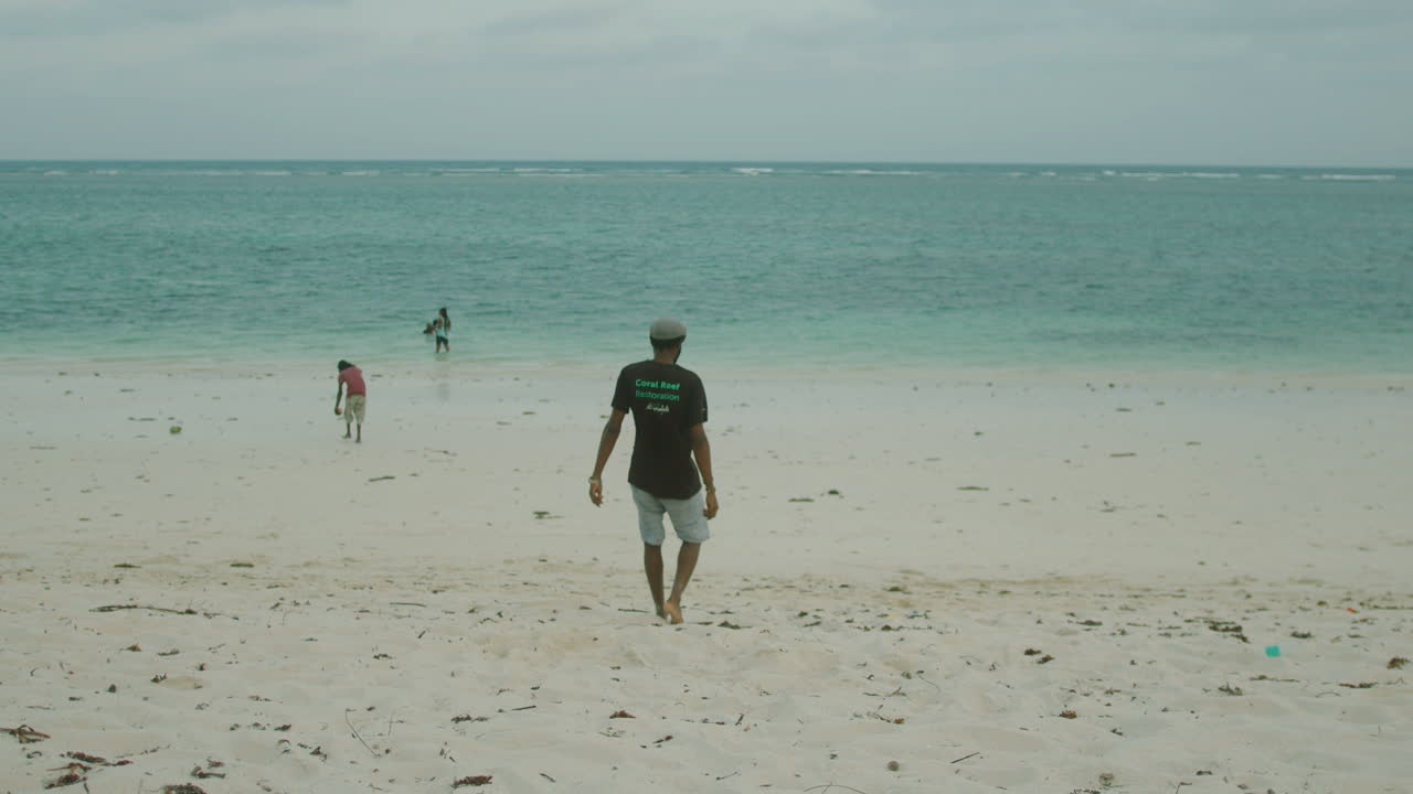 toma general de un joven negro que va de la orilla al mar en cámara lenta