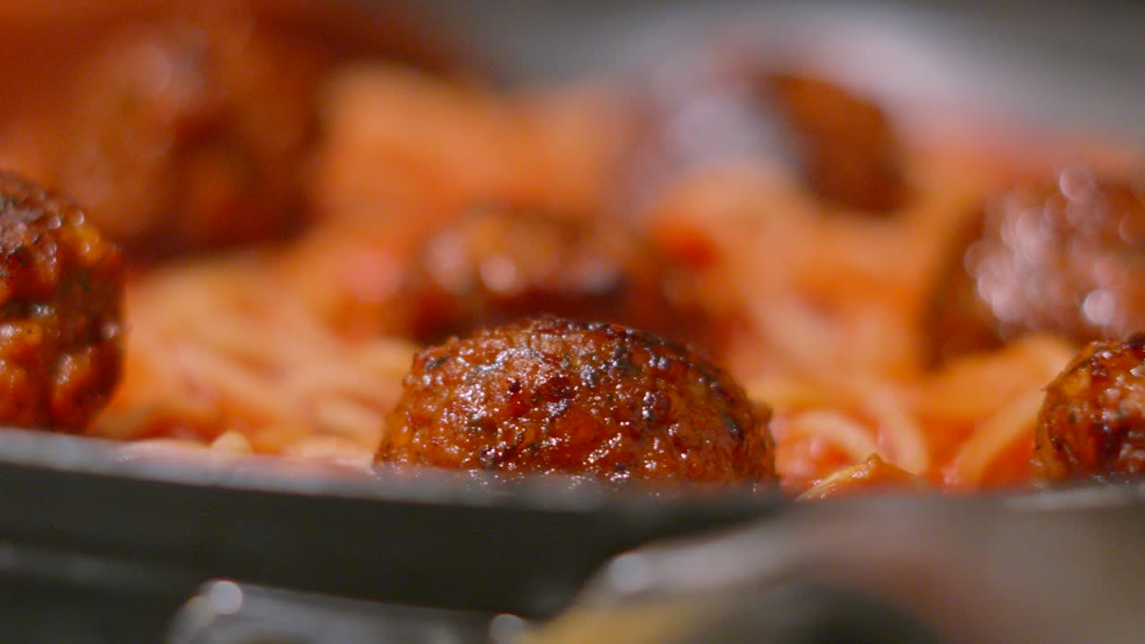 Close Up of Delicious Italian Meatballs Resting in Pan with Spaghetti Pasta in Rich Tomato Sauce with Herbs. Homemade Cooking Food Footage.