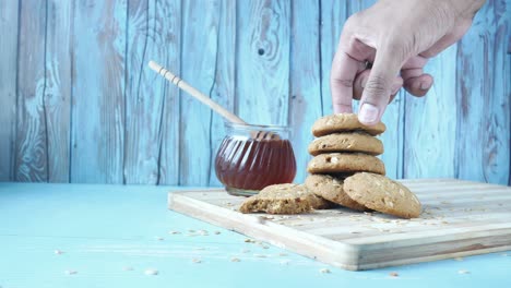 hand reaching for a stack of oatmeal cookies with honey