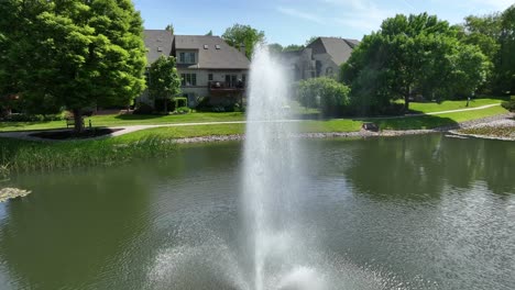 Drone-view-of-a-community-of-townhouses-in-a-private-community-with-a-park-setting,-a-small-lake-and-a-fountain