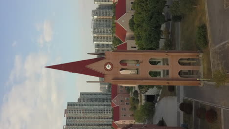 Vertical-format:-aerial-flies-to-drone-pilot-in-city-clock-tower