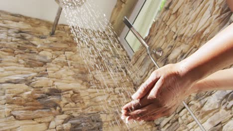 Video-of-hands-of-african-american-woman-showering-with-water