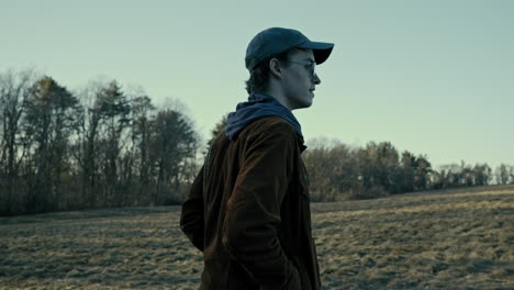 young photographer walks through an open field on a winter evening