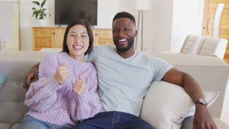 retrato de una feliz pareja diversa abrazándose en la sala de estar