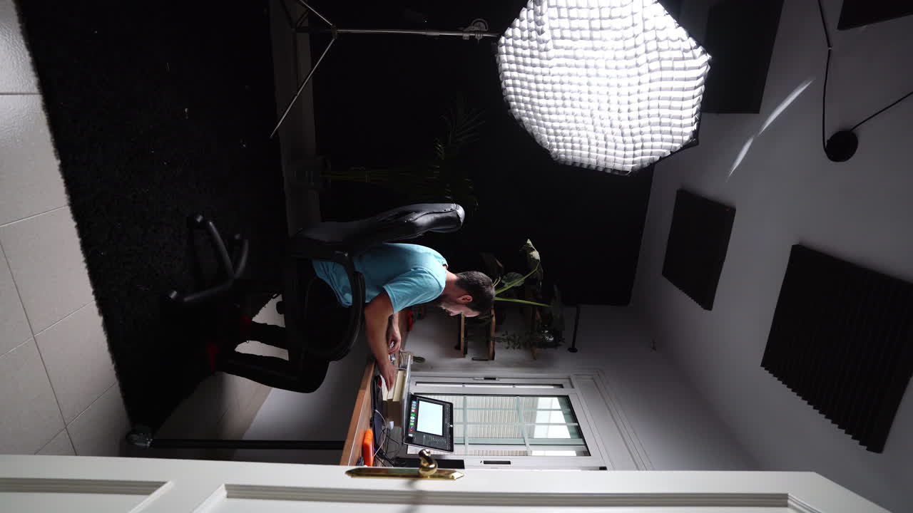 joven profesional independiente vertical que trabaja solo en su estudio moderno sentado en una silla con computadora portátil e iluminación, proceso creativo desarrollando una nueva idea