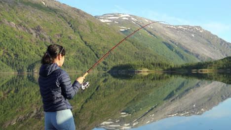 woman fishing on fishing rod spinning in norway.