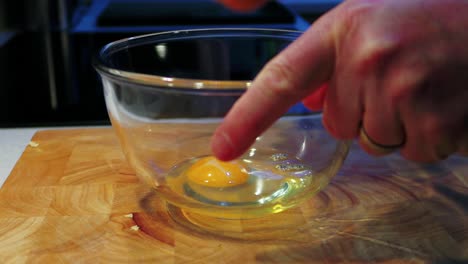 cracking 3 fresh eggs into a glass bowl