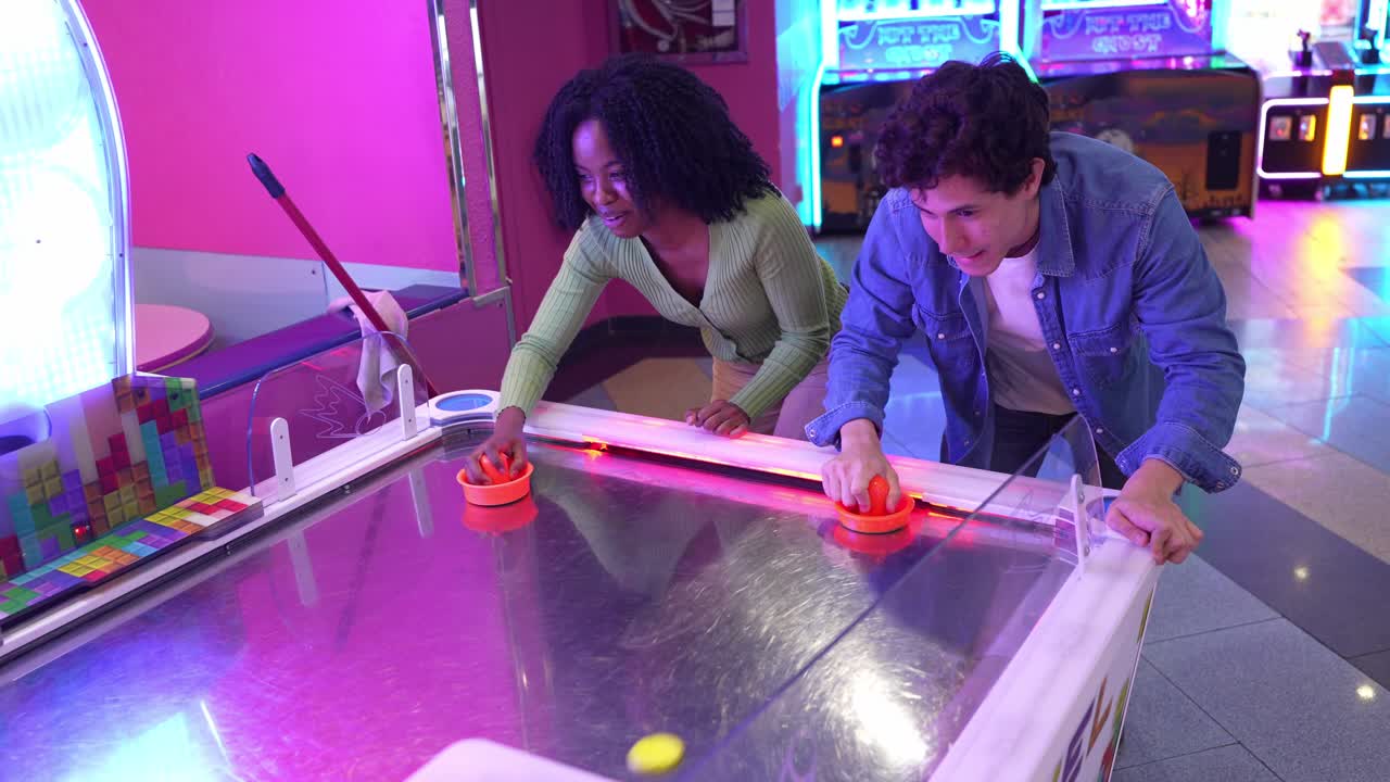 Amici che giocano a air hockey in una sala giochi