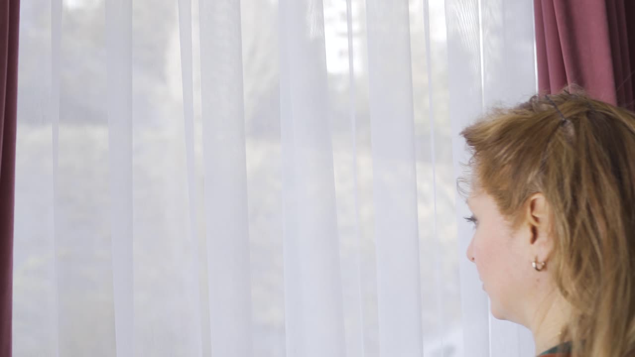 집에서 창밖을 바라보는 사려 깊은 성숙한 여성.