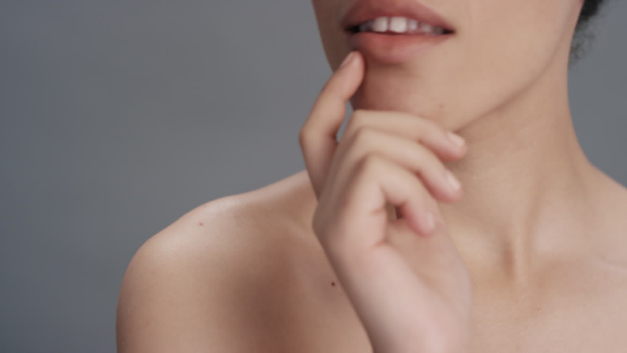 retrato de belleza de cerca mujer joven atractiva tocando el rostro con la mano acariciando una piel sana y perfecta disfrutando del cuidado natural de la piel sobre un fondo gris