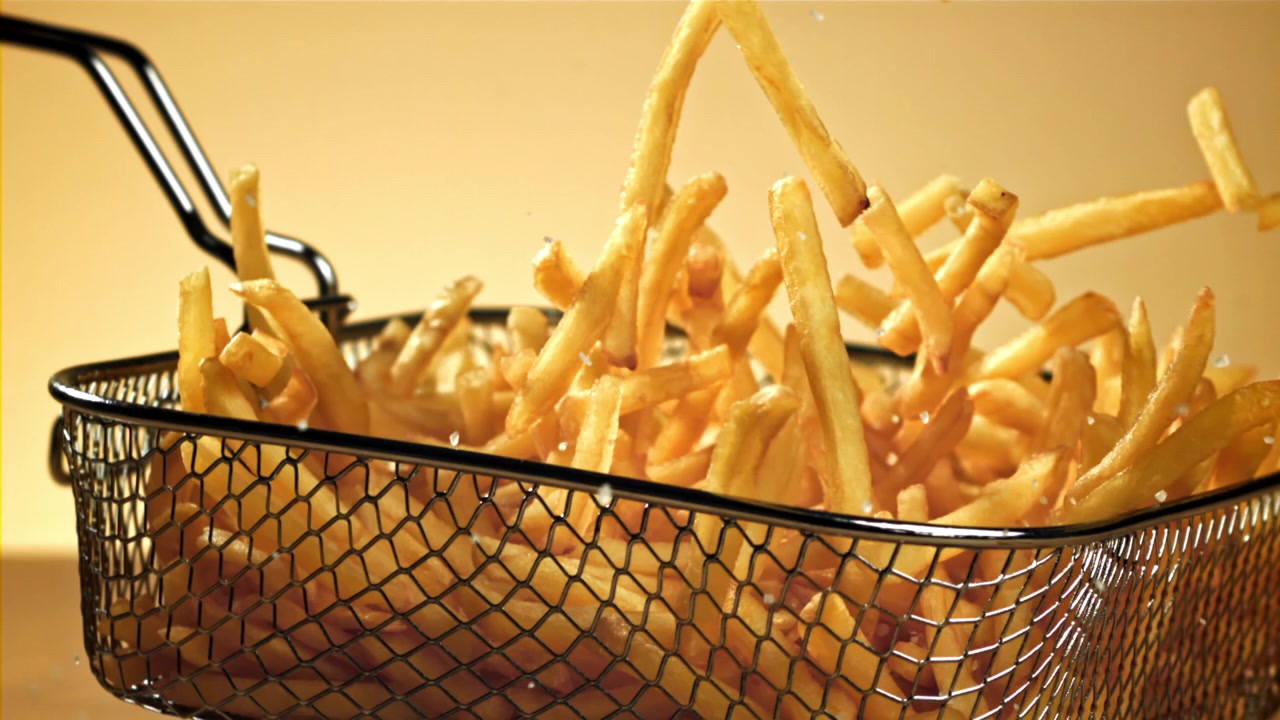 Zeitlupe von Salz, das auf knusprige Pommes Frites fällt